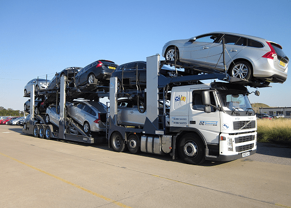 A car carrier truck hauling several Volvo station wagons