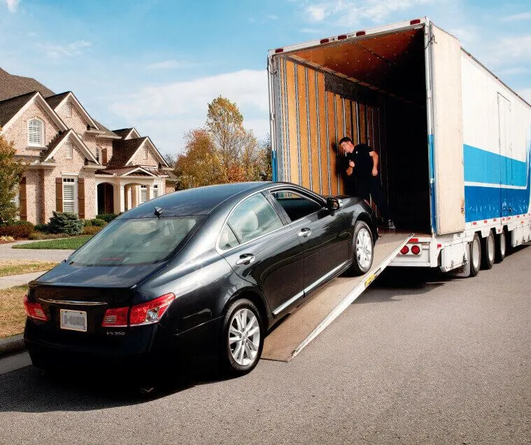 An enclosed auto transport truck with a car being loaded